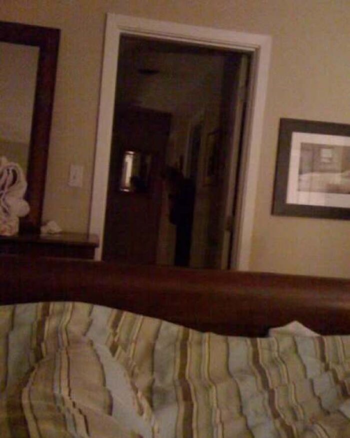 A shadowy figure standing in a dark doorway, captured in real-life photos like a horror movie.