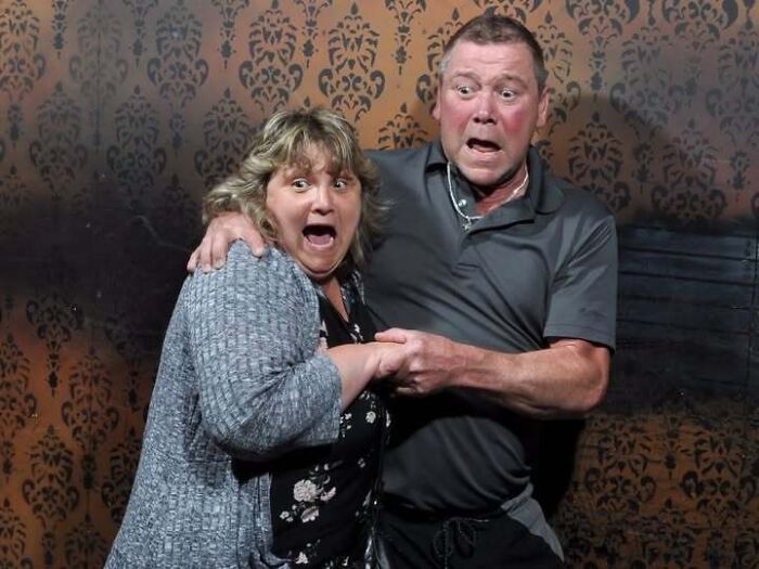 Frightened couple holding hands in fear inside a haunted house photo moment