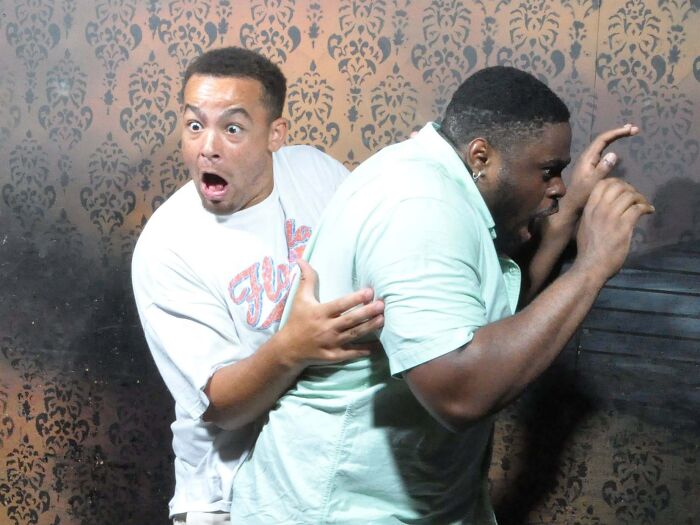 Scared man grabbing another friend in fear captured in haunted house photos