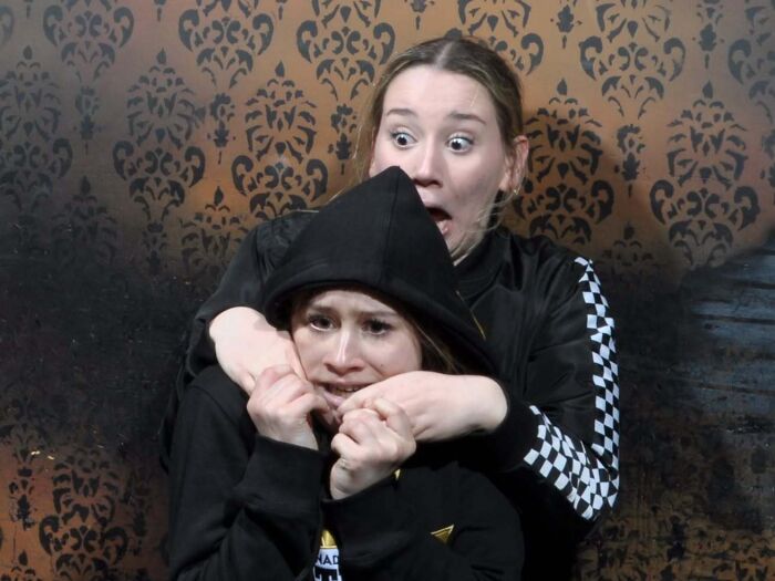 Two women look wide-eyed and terrified in a dramatic haunted house photo.