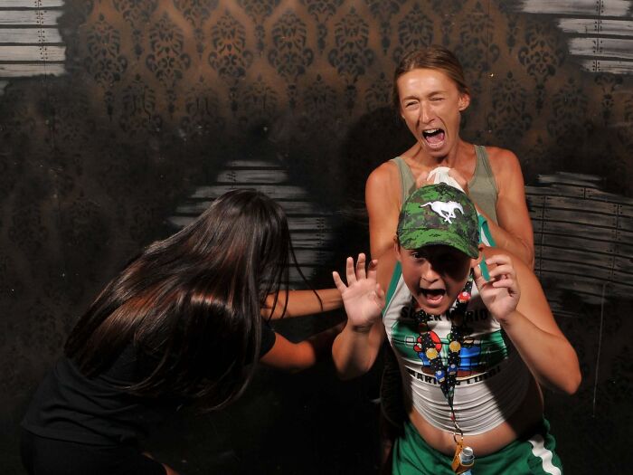 Funny haunted house photo of terrified people screaming in shock inside Nightmares Fear Factory attraction.