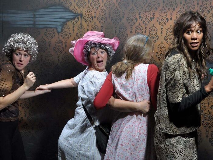 People in funny costumes reacting with fear in a haunted house photo.