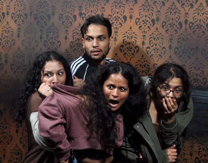 Group of startled people in a haunted house photo looking terrified.