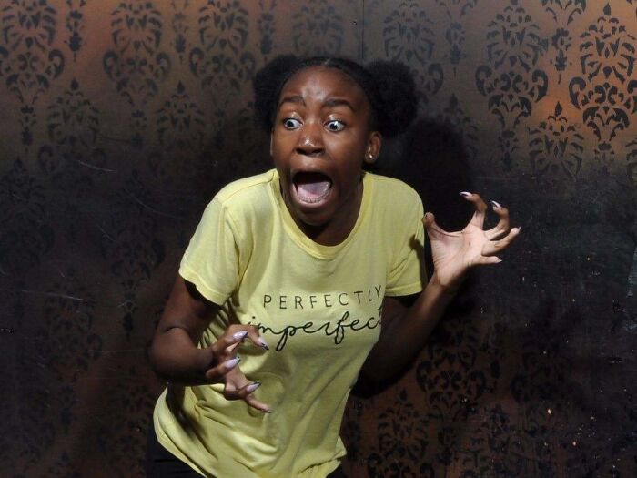Girl in yellow shirt screaming in a funny haunted house photo.