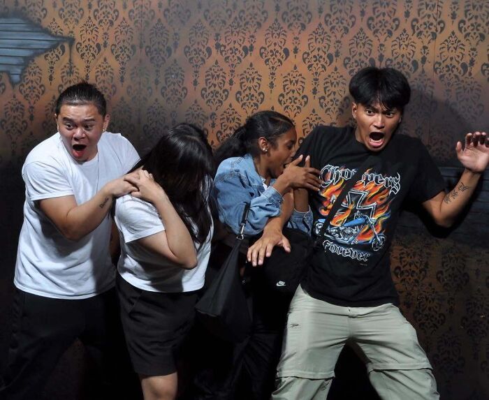 Group of friends terrified inside a haunted house photo with shocked expressions.
