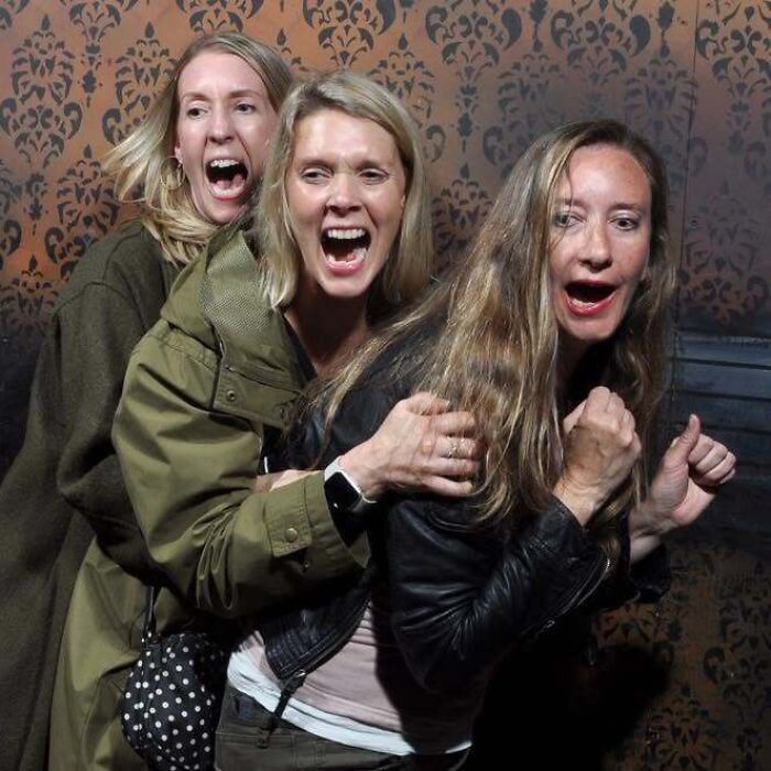 Three women screaming in terror during a haunted house visit.