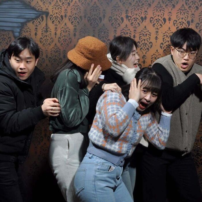 Scared visitors cowering and covering their ears inside a spooky attraction in haunted house photos.