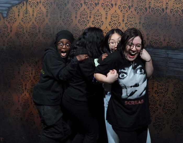 Group of terrified friends huddling together tightly in one of the hilarious haunted house photos.