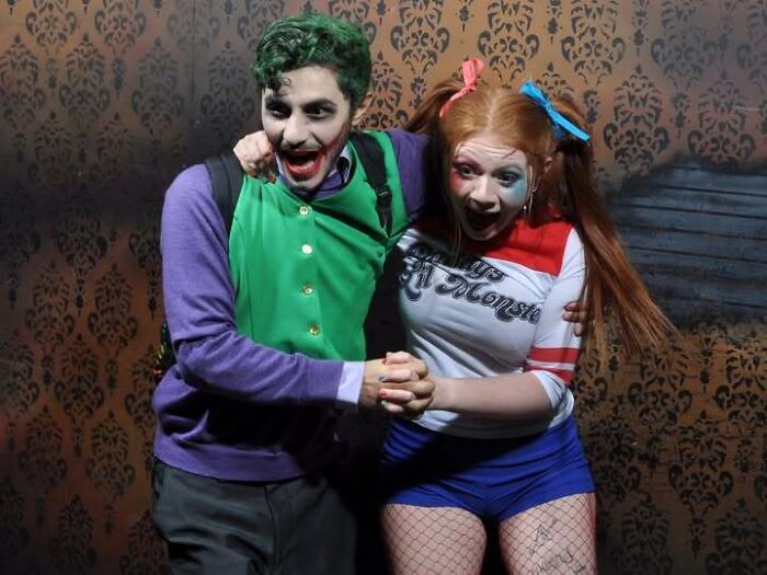 A couple dressed in Joker and Harley Quinn costumes smiling in one of the funny haunted house photos.