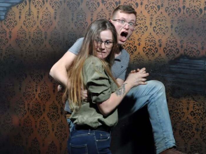 Scared young couple holding each other tightly in a haunted house photo