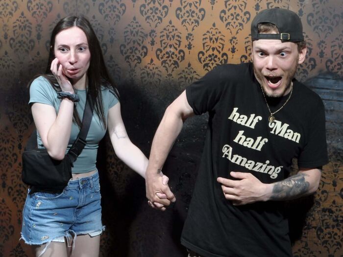 Terrified couple holding hands during a hilarious haunted house photo moment