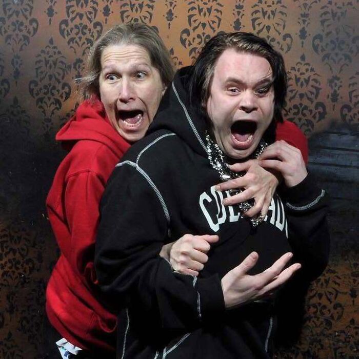 Two people scream in hilarious shock inside a haunted house photo capture.