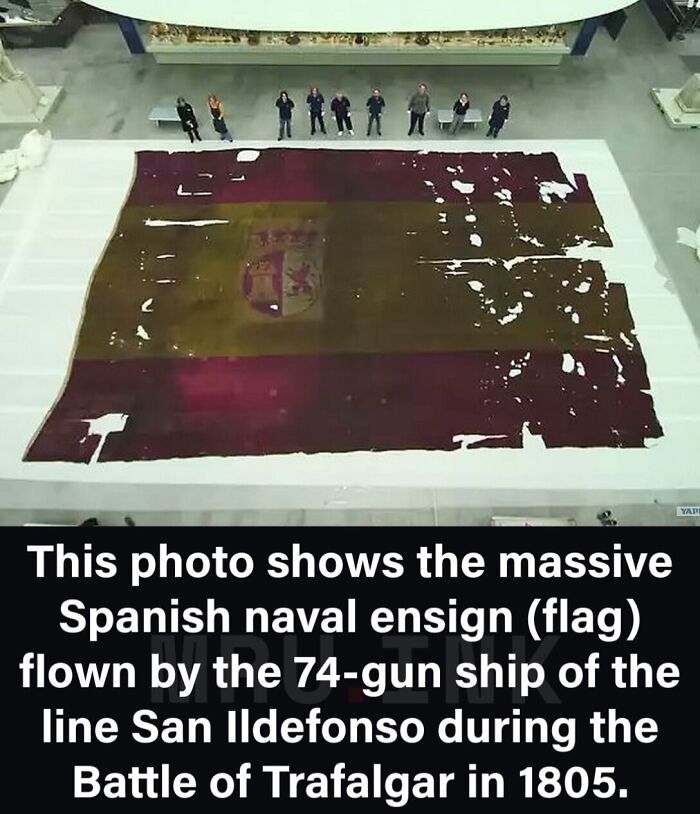 A massive historical Spanish naval flag displayed on a floor, as seen in fascinating photos and facts.