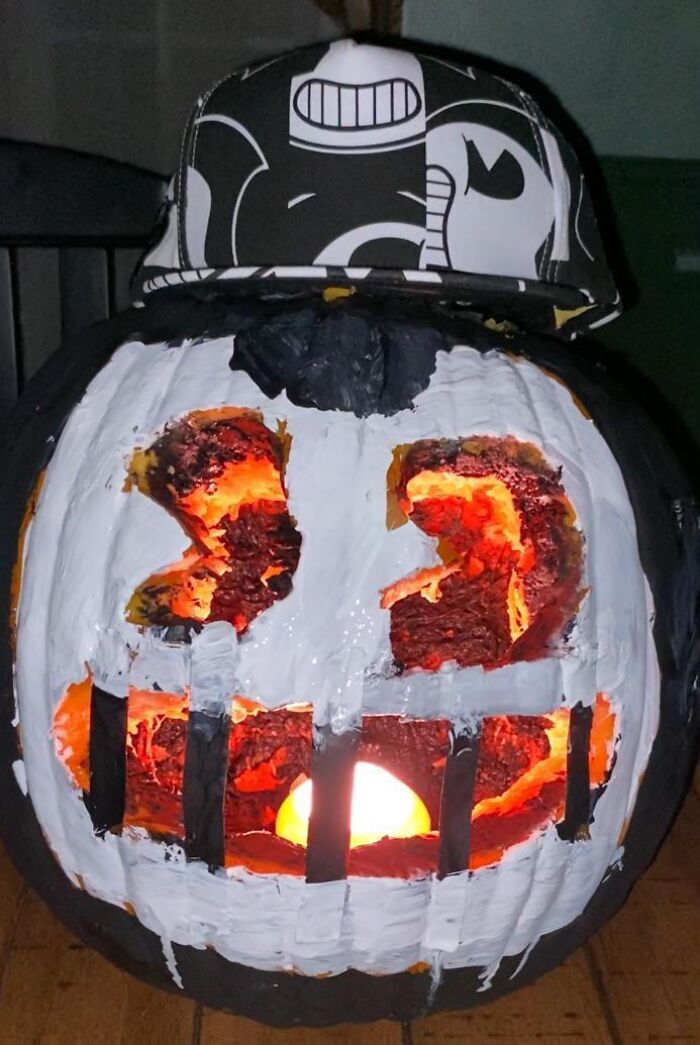 A funny, poorly carved Jack-o'-lantern wearing a hat that didn’t go as planned.