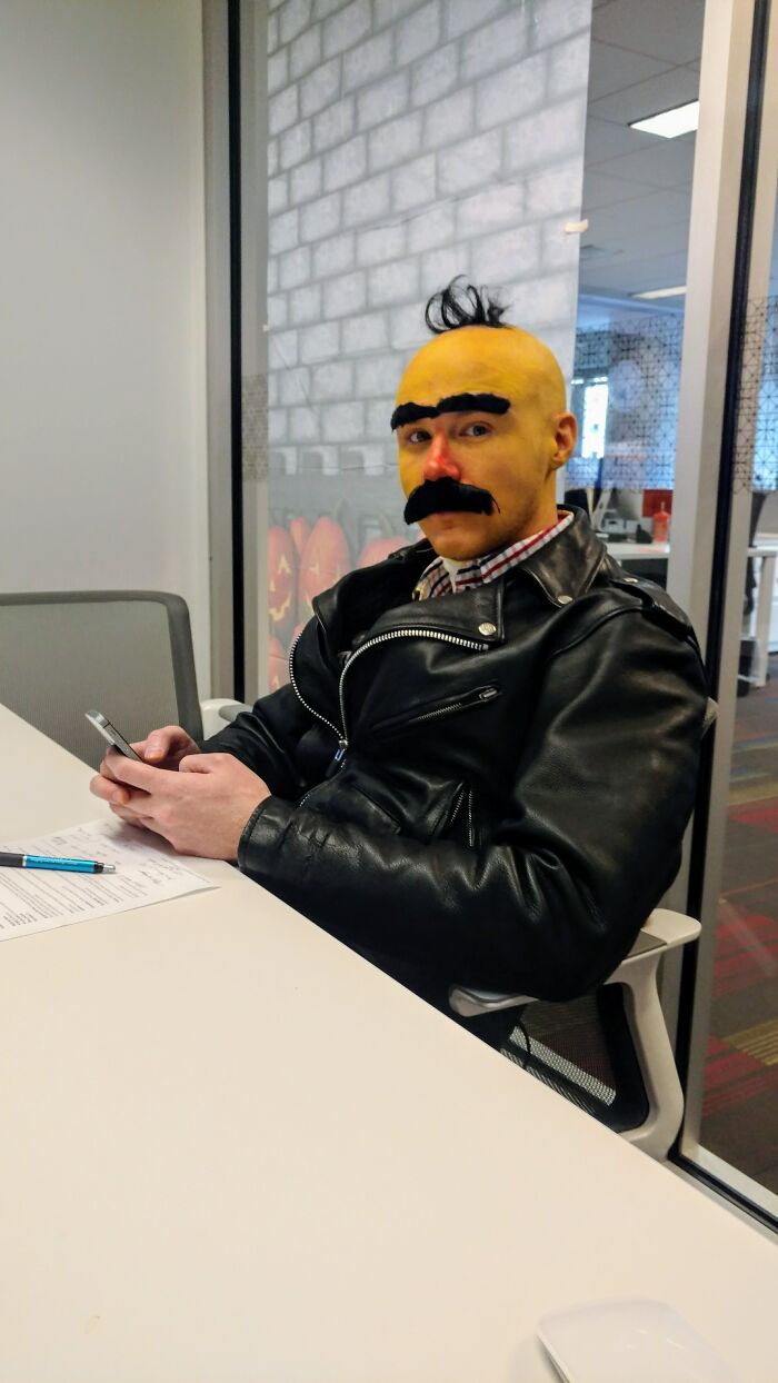Man wearing a funny Bert Halloween costume sitting at an office desk.