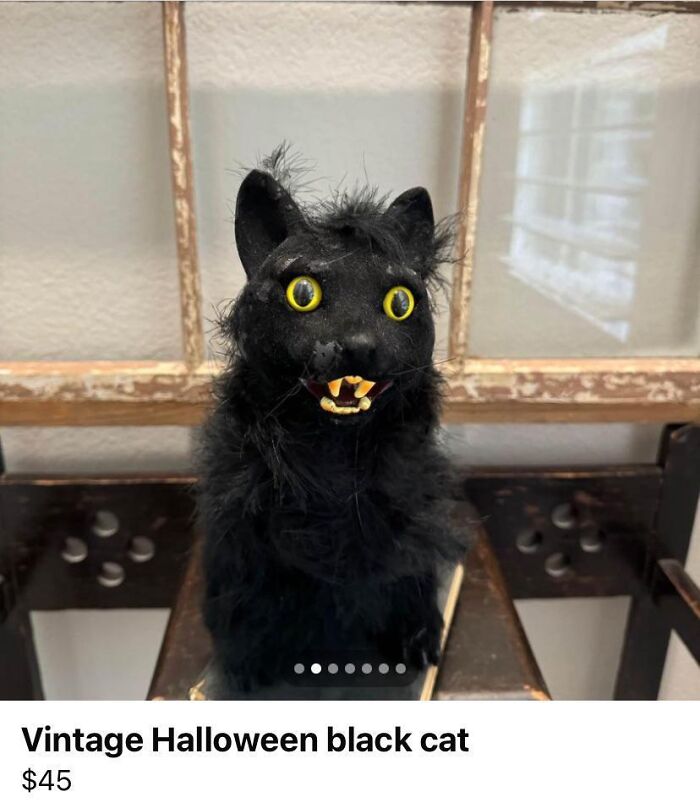 A bizarre vintage Halloween black cat prop with wild yellow eyes and pointy teeth