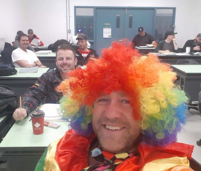 Funny Halloween selfie of a man wearing a bright rainbow clown wig in class.
