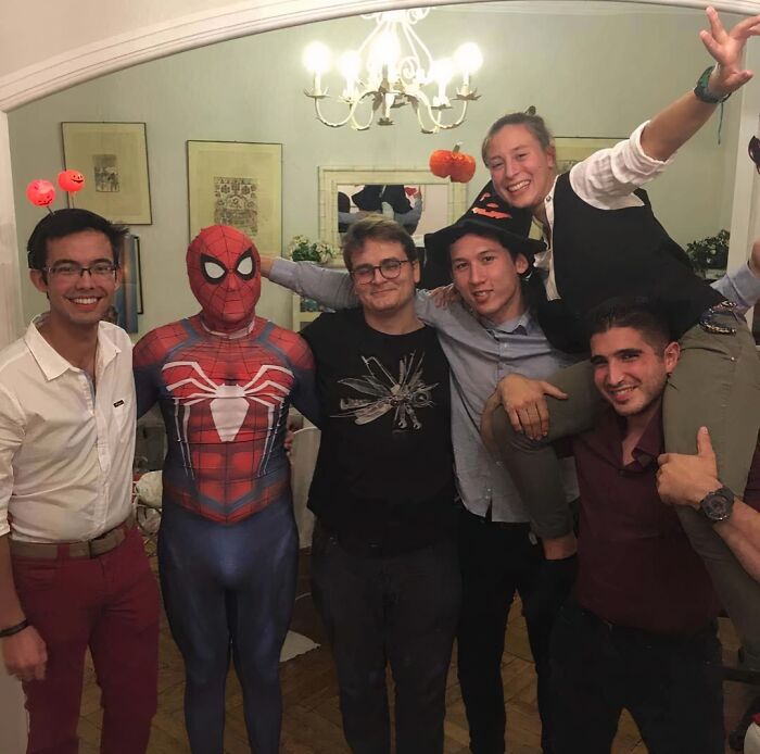 Funny Halloween group photo featuring a man in a Spider-Man suit.