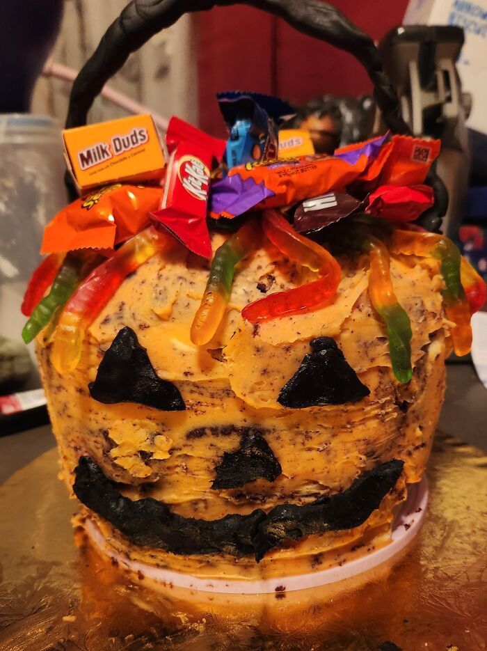 A funny pumpkin-themed Halloween cake decorated with candy and gummy worms