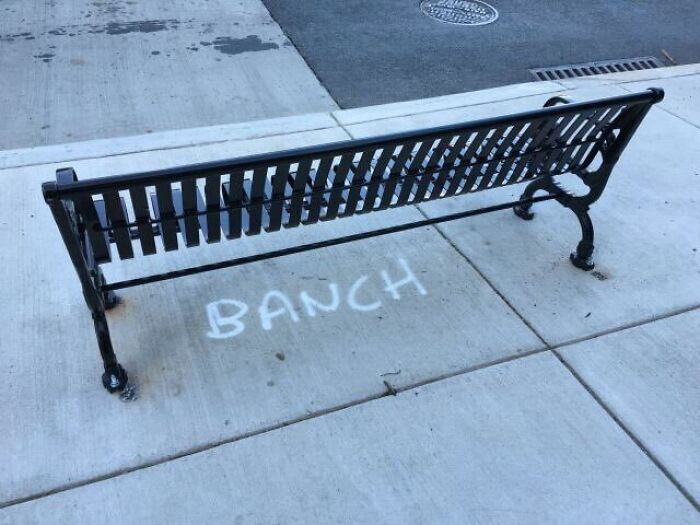 A park bench with the word BANCH spray painted on the sidewalk, a hilarious spelling fail