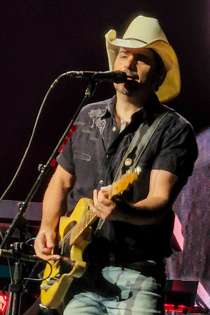Country music singer Brad Paisley wearing a cowboy hat and playing electric guitar on stage