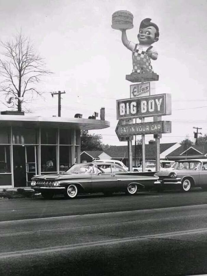 Black and white vintage photo of a Big Boy drive-in restaurant with vintage cars parked outside.