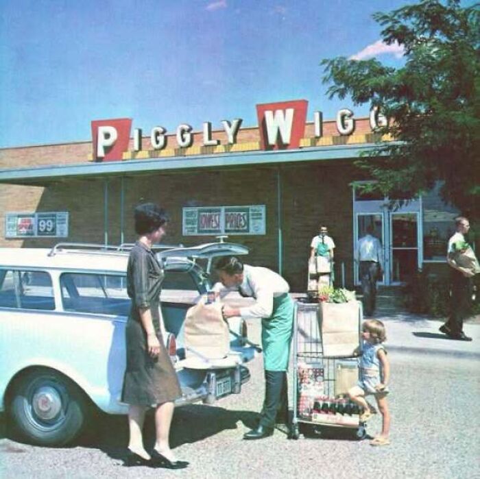 Old photo of a family loading groceries into a car outside a Piggly Wiggly supermarket in America.
