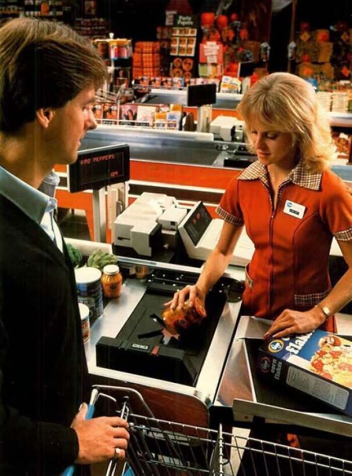 Old photo of a cashier scanning items at a supermarket checkout line in classic America.