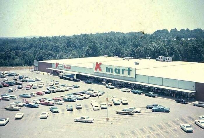 Aerial view old photo of a Kmart store and busy parking lot surrounded by trees in America.