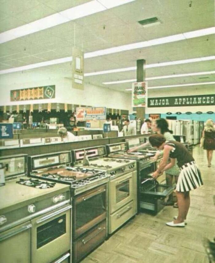 Woman browsing vintage gas and electric stoves in an appliance store showroom from old photos of America.