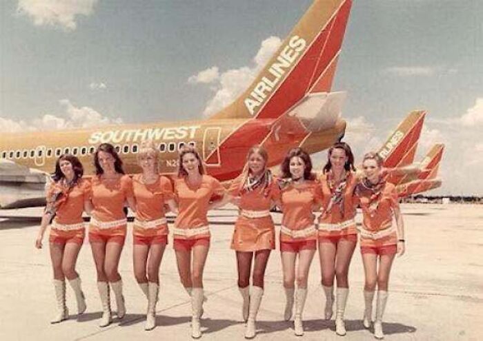 Flight attendants in orange uniforms posing in front of planes in old photos of America.