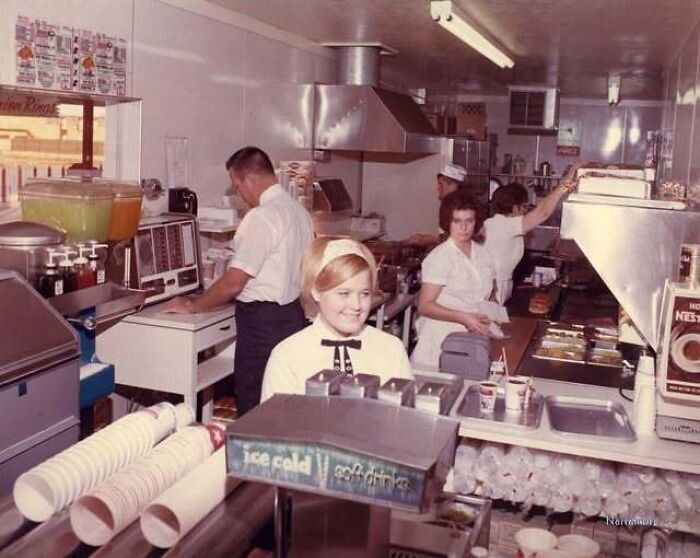 A vintage photo showing staff working inside a classic fast food kitchen in mid-century America.