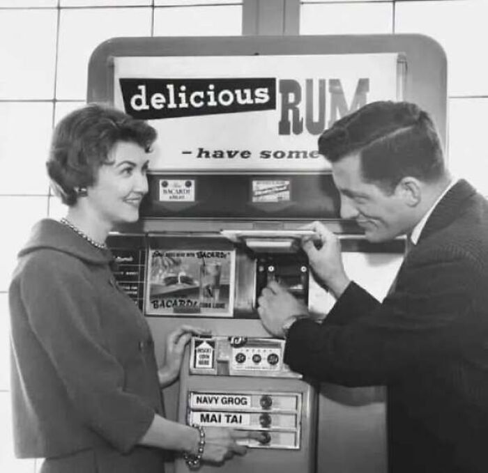 Man buying drinks from a vintage rum vending machine featured in old photos of America.