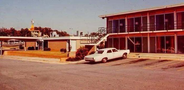 A vintage white car parked outside a classic Holiday Inn motel, captured in old photos of America.