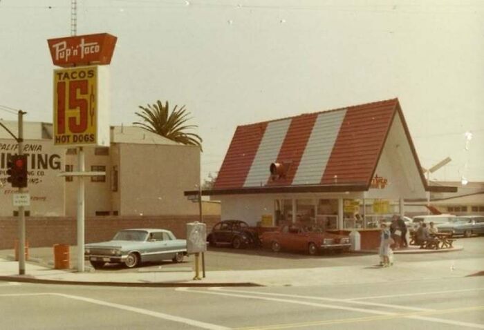 A vintage Pup 'N Taco fast-food restaurant drive-in showing vintage cars, from old photos of America.