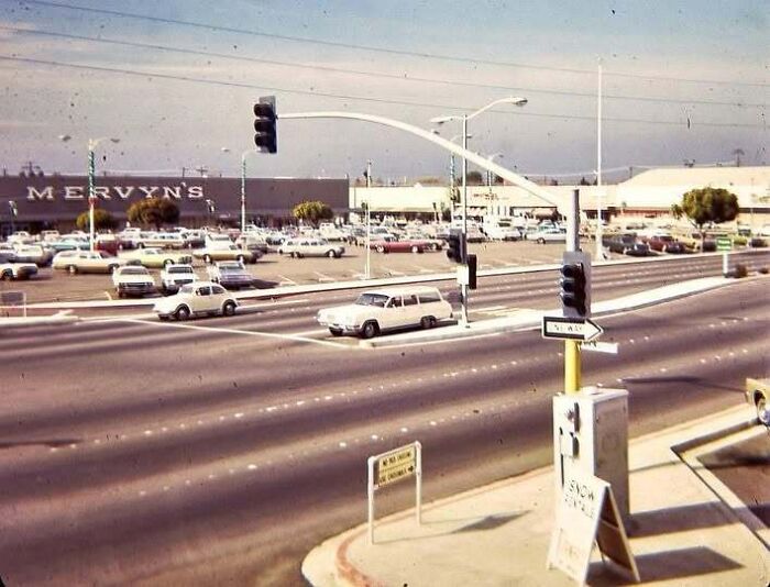 A vintage street scene with classic cars in an old photo of America outside a Mervyn's department store.