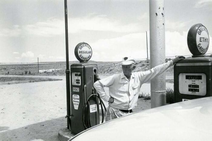 A gas station attendant posing by vintage fuel pumps featured in old photos of America.
