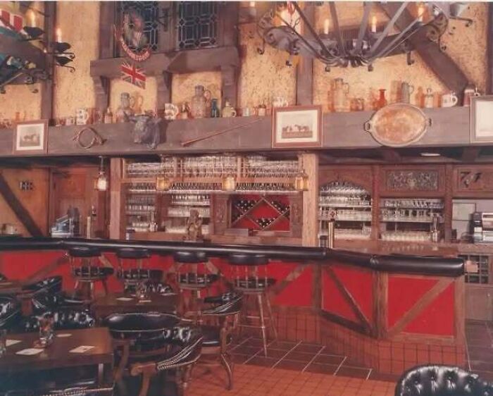 A cozy vintage bar interior showing old photos of America style rustic decor with wooden beams and a large chandelier.