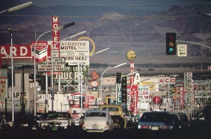 Vintage old photo of America showing a busy highway full of cars and bright motel neon signs