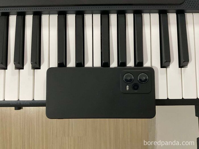 Black smartphone lying across piano keys showcasing arbitrary measurement memes avoiding the metric system.