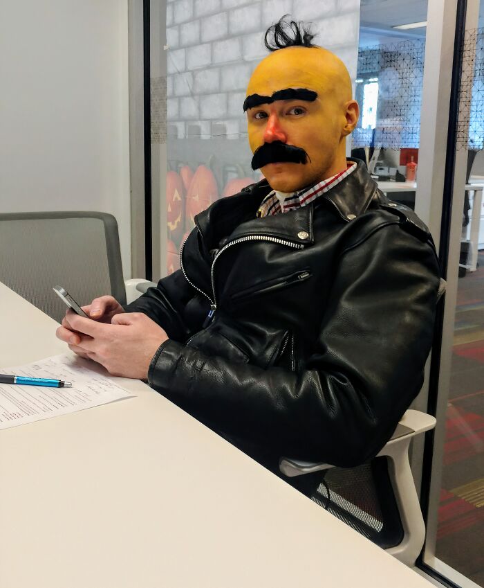 Man wearing a funny Bert Halloween costume sitting at an office desk.