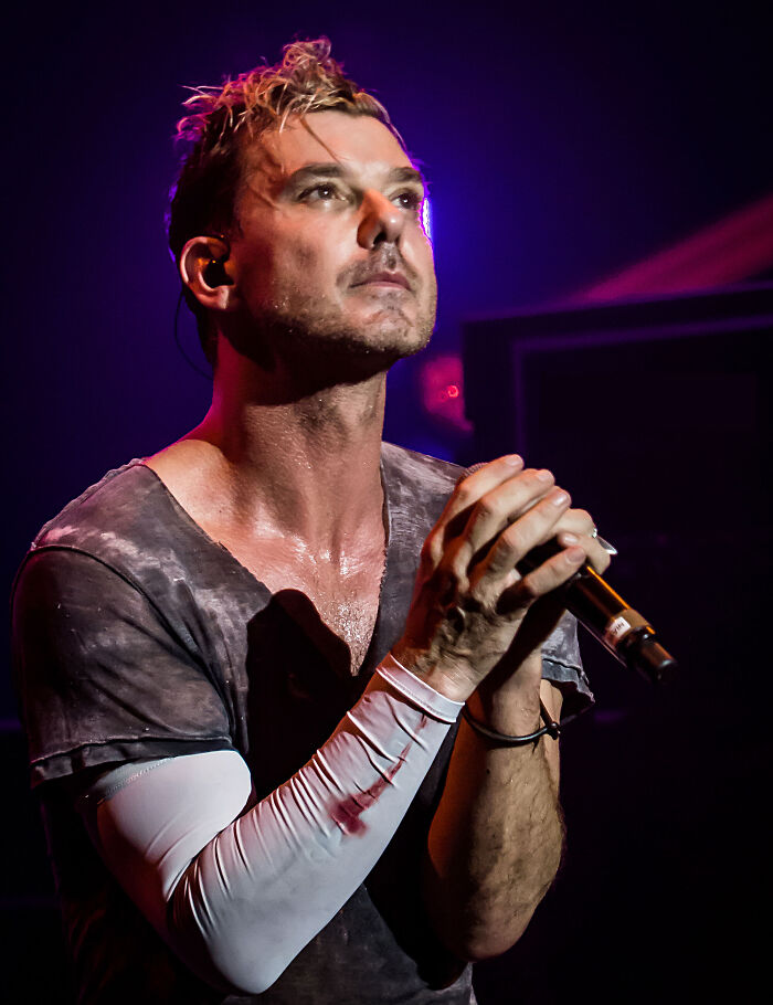 Musician Gavin Rossdale singing into a microphone on stage during a concert performance.