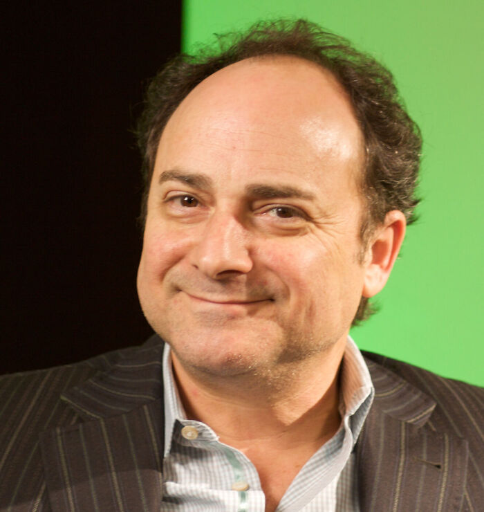 Actor and comedian Kevin Pollak smiling in a pinstripe suit jacket.