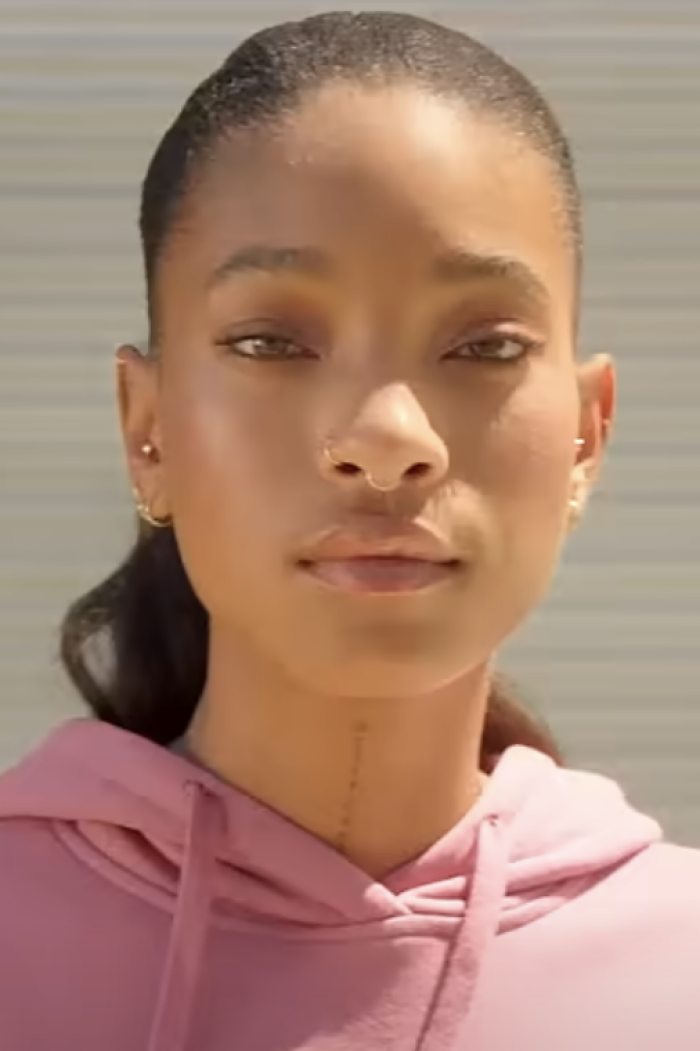 Close-up portrait of Willow Smith wearing a pink hoodie and nose ring.