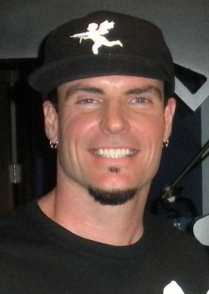 Rapper Vanilla Ice smiling in a black baseball cap and t-shirt during a career highlights event.