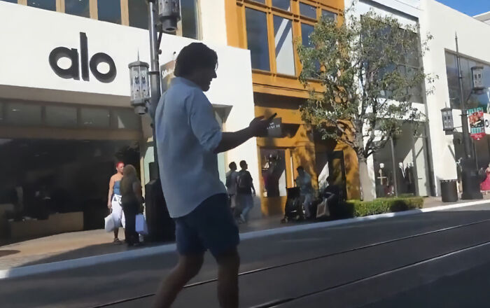LA women warning: manosphere adherent looks at his phone while walking outside.