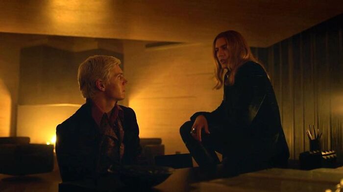 Two characters in dramatic, dark lighting discussing intense Halloween conflicts in a dimly lit room.
