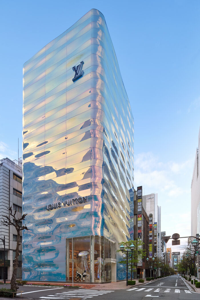 Louis Vuitton building with a reflective wavy glass facade under blue sky