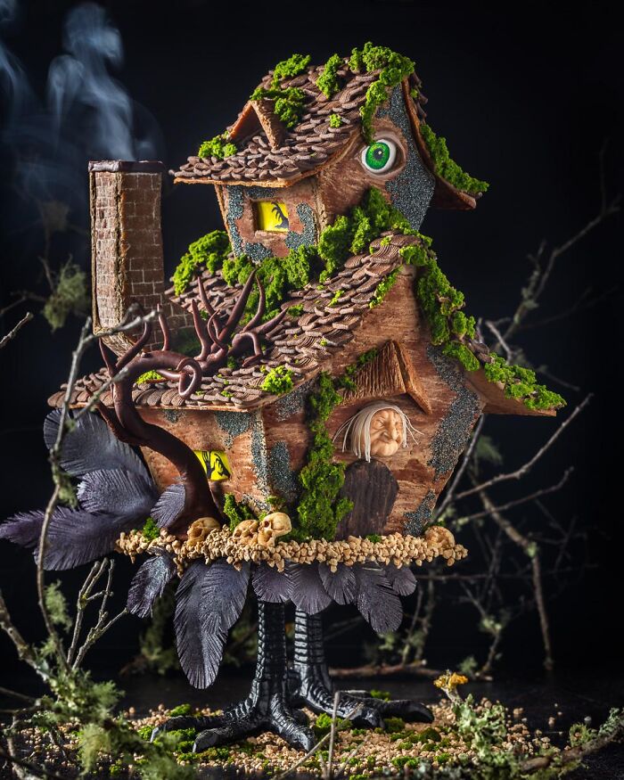 Intricate Baba Yaga witch house cake made as spooky Halloween foods with edible moss and chicken feet.