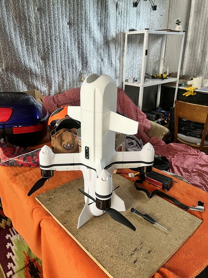 A white drone assembled on an orange workspace using custom 3D prints.